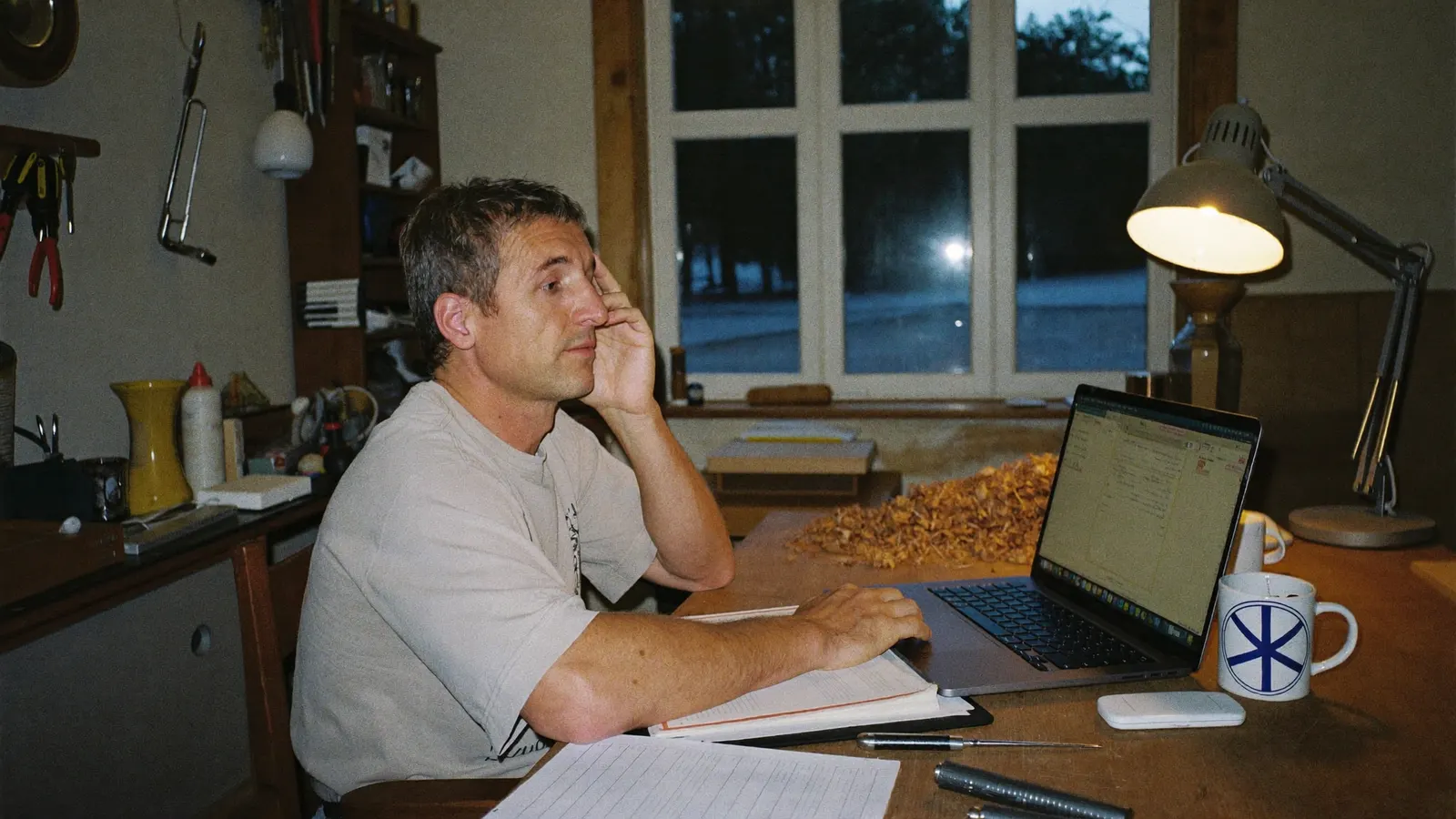 Schreiner sitzt abends am Laptop in seiner Werkstatt