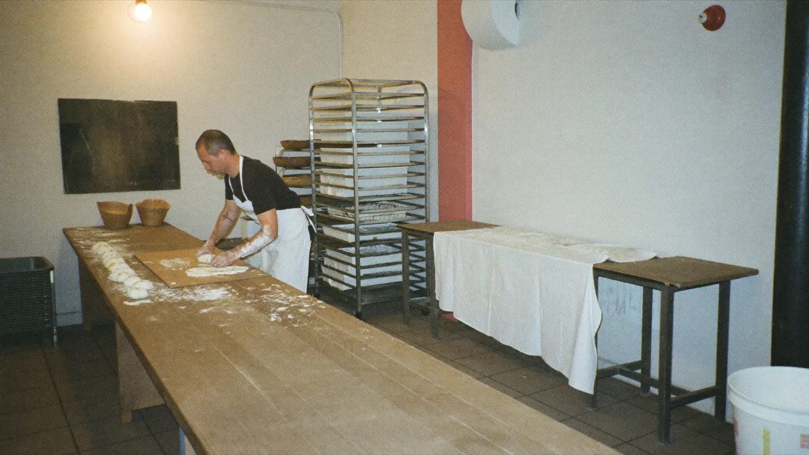 Bäcker allein in der Backstube, der zweite Arbeitsplatz neben ihm ist leer