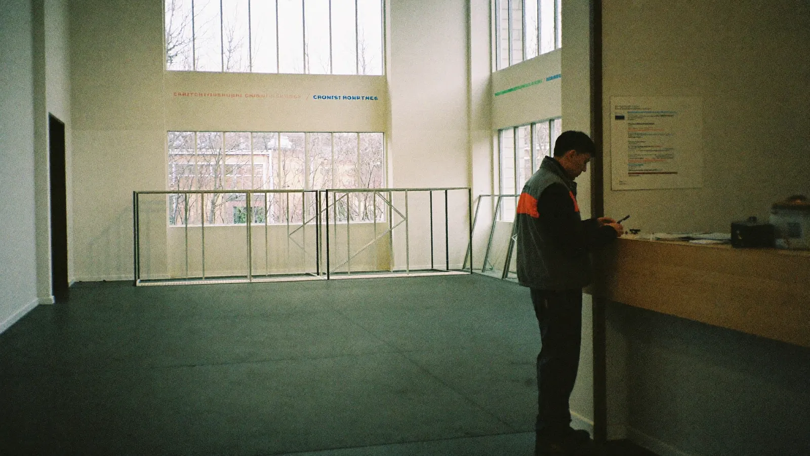 Leerer Showroom mit grosser Fensterfront, ein Mann wartet am Tresen mit dem Handy